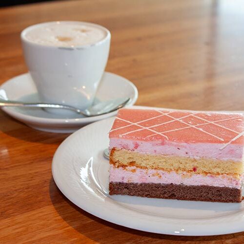 1 Stück Erdbeer-Obers Schnitte vor 1 Tasse Kaffee