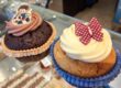 Ein Muffin aus dunklem Teig und ein Muffin aus hellem Teig, jeweils mit Creme oben drauf und einer Verziehrung.
